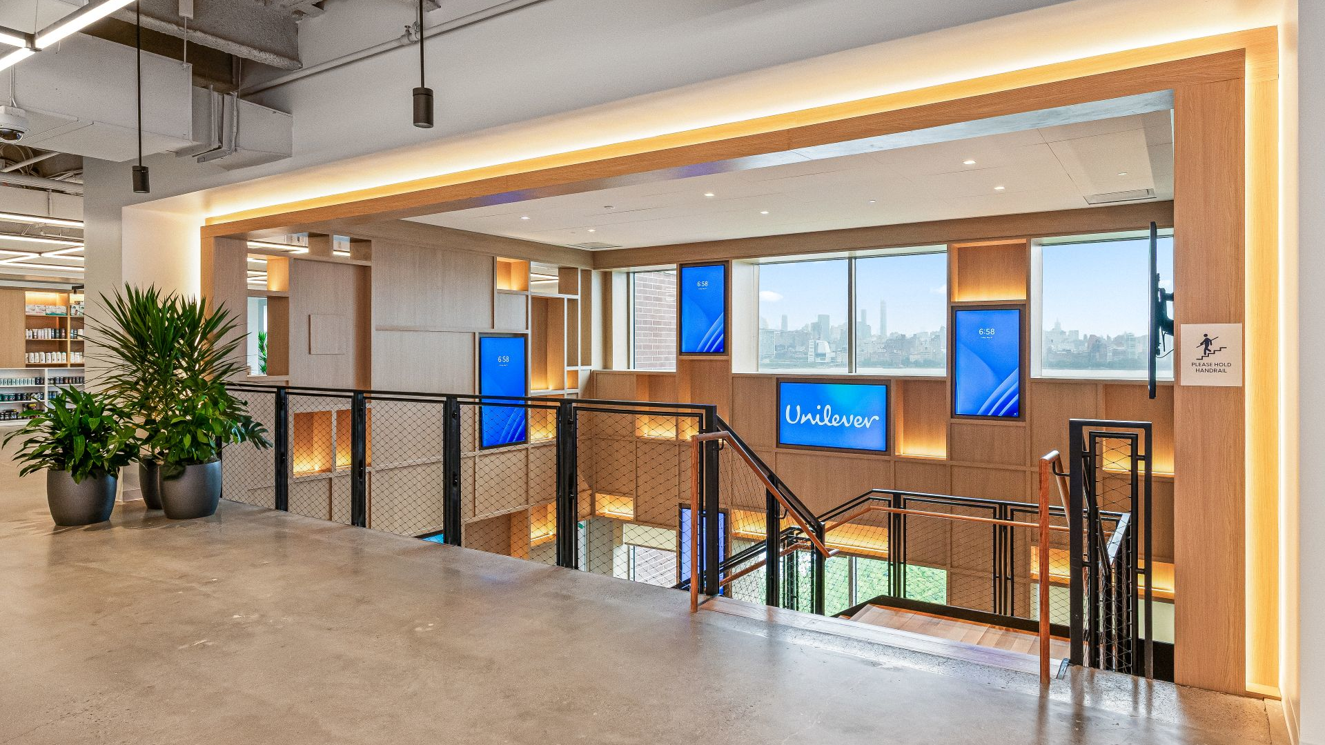A natural wood stairway with black railings overlooking the New York City skyline.