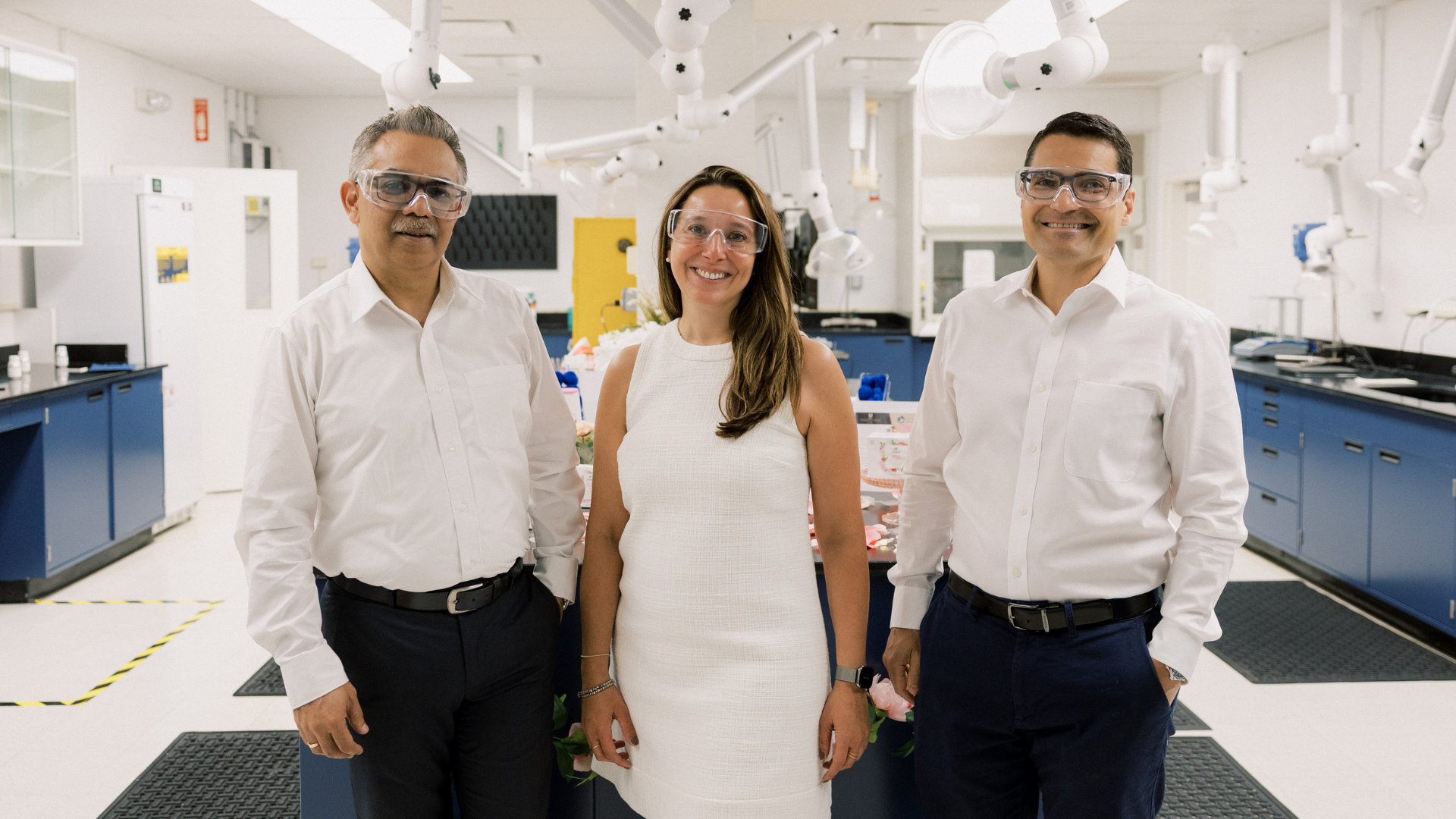 Three Unilever leaders stand side-by-side, looking at camera. Scientific R&D equipment is seen in the background.