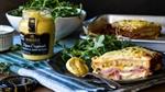 A ham and cheese sandwich served with arugula and Dijon mustard, alongside a jar of Maille mustard.