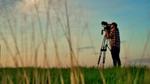 Man filming in a field at dusk