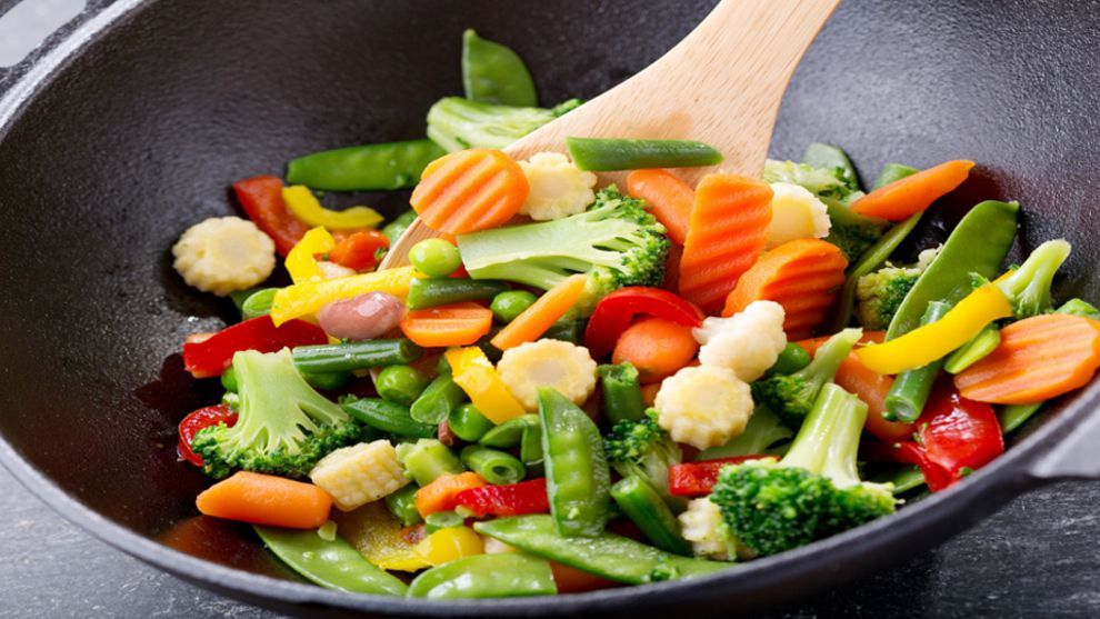 Wok pan with variety of colorful vegetables being stirred