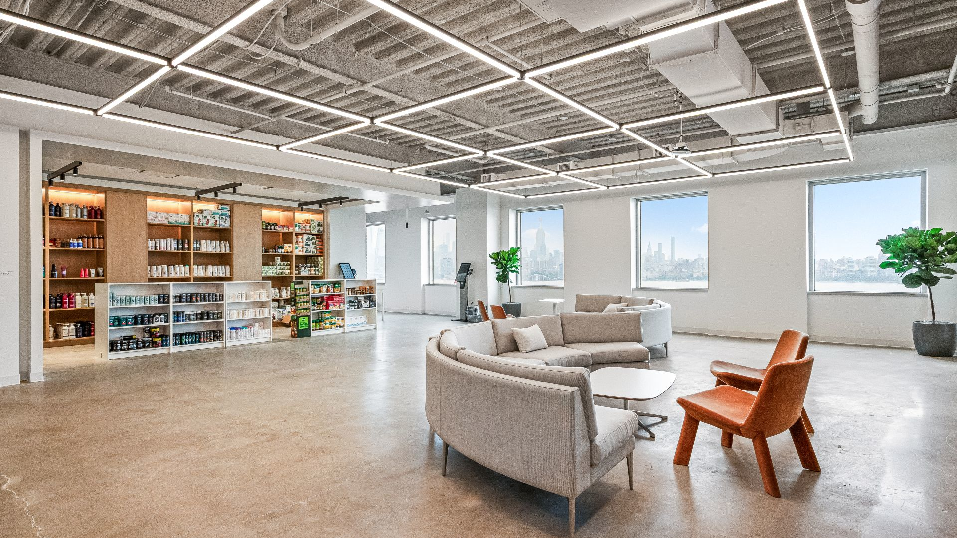 Unilever's company store with products on shelves, and a curved gray couch sitting area. The windows feature view of NYC skyline.